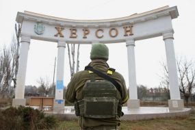 Ukrainian military man near the arch with the inscription "Kherson"
