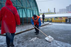Працівниця комунальної служби чистить сніг біля входу в метро