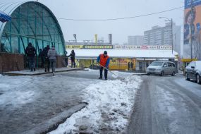 Працівниця комунальної служби чистить сніг біля входу в метро