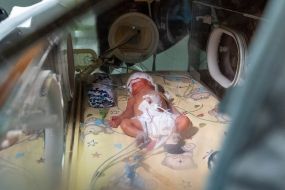 A premature baby lies in a box in the neonatal intensive care unit at the Neonatology Center
