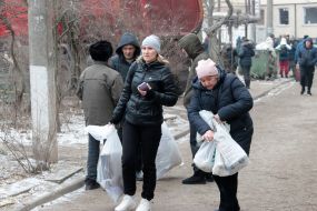 People carry essential items to the destroyed house