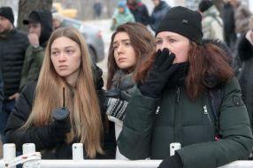 People are waiting near a house destroyed by rocket fire