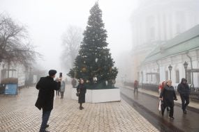 A woman takes a photo near a Christmas tree