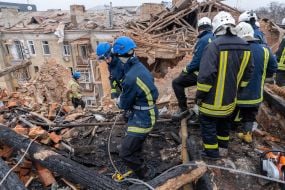 Rescuers on the roof of residential building dilapidated as a result of shelling