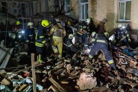 Rescuers near a residential building dilapidated as a result of shelling
