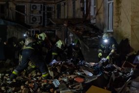Rescuers near a residential building dilapidated as a result of shelling