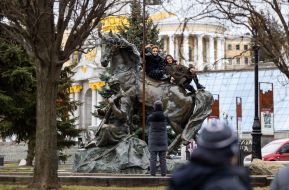 A woTeenagers are photographed near the monument to Cossack Mamai on Independence Square