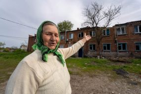A local woman shows a destroyed house