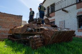 Police officers inspect a burned-out Russian tractor MTLB