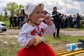 A girl in an embroidered dress eats ice cream