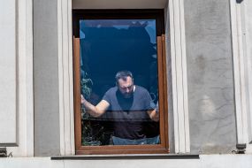 A man removes broken glass from a window