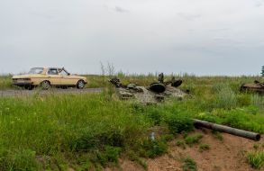 The car drives past the towers of blown-up tanks in the Kharkiv region