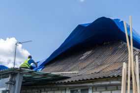 Volunteers are repairing the roof of a destroyed house
