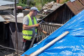 Volunteers are repairing the roof of a destroyed house