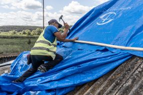 Volunteers are repairing the roof of a destroyed house
