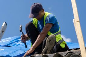 Volunteers are repairing the roof of a destroyed house