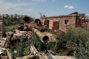 Destroyed Russian tank in the yard of a destroyed house