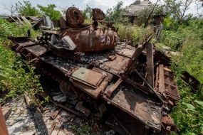 Destroyed Russian tank in the yard of a destroyed house