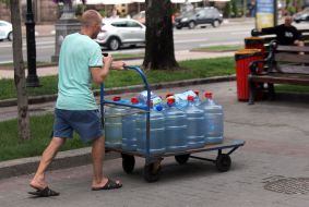 An employee pushes a wheelbarrow with empty water bottles