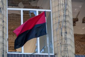 Red-black flag against the background of the destroyed building of the Kupyansky City Council
