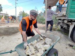 Volunteers clear broken bricks from the yard of one of the private houses destroyed by the Russian occupiers in the village of Gorenka