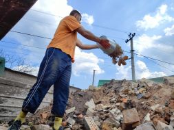 Volunteers clear broken bricks from the yard of one of the private houses destroyed by the Russian occupiers in the village of Gorenka