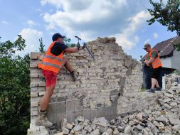 Volunteers clear broken bricks from the yard of one of the private houses destroyed by the Russian occupiers in the village of Gorenka