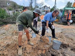 Volunteers clear broken bricks from the yard of one of the private houses destroyed by the Russian occupiers in the village of Gorenka