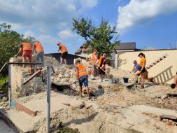 Volunteers clear broken bricks from the yard of one of the private houses destroyed by the Russian occupiers in the village of Gorenka