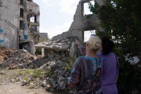 Women near a house destroyed by an aerial bomb dropped from a Russian plane in the city of Izium