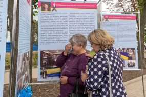 Місцева мешканка біля стенду виставки, присвяченого українському письменнику, вбитому російськими солдатами Володимиру Вакуленку