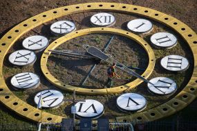 A municipal service worker mows the grass on the face of a flower clock in Kyiv