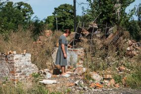 Former librarian Larisa Rudenko stands on the ruins of the library destroyed by the Russian occupiers in March 2022