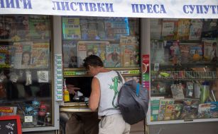 A man near a newspaper kiosk on the street in Kyiv