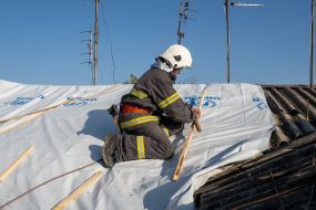 A fireman on the roof of a house damaged by a bomb explosion