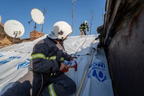 A fireman on the roof of a house damaged by a bomb explosion