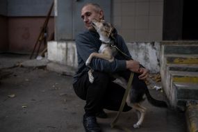 A man with a dog on the street near a residential building in the Ostriv district of Kherson