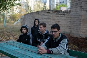 Teenagers sit at a table in the yard of a residential building in the Ostriv district of Kherson