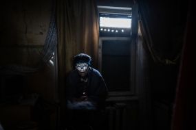 A woman with a flashlight on sits in the dark in an apartment (Ostriv district) in Kherson