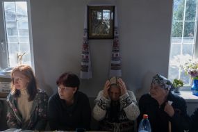 Women sit at a table under an icon in a church building
