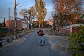A man with a wheelbarrow walks down the street (Ostriv district) in Kherson