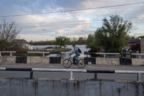 A man rides a bicycle across a bridge (Ostriv district) in Kherson