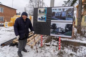 An elderly man near a residential building that is being rebuilt after Russian shelling