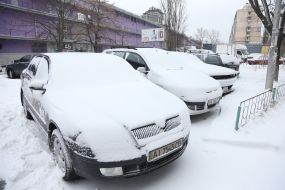 Укрытые снегом припаркованные автомобили на улице в Киеве
