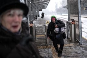 Літня жінка з  великою сумкою на плечі на засніженій вулиці в Києві