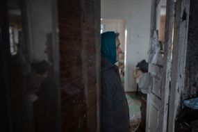 Жінка в пошкодженому внаслідок ракетного обстрілу  будинку