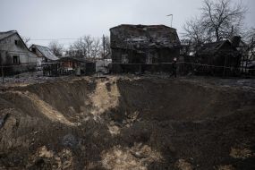 Вирва біля пошкодженого внаслідок ракетного обстрілу будинку