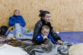 Евакуйовані зі зруйнованих у наслідку удару дронів житлових будинків жінки та дитина у тимчасовому притулку в Одесі