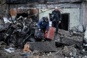 Люди выносят вещи из разрушенного в результате российских ракетных обстрелов жилого дома в Киеве