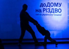 A silhouette of a man and a child and the inscription "Home for Christmas" on the wall